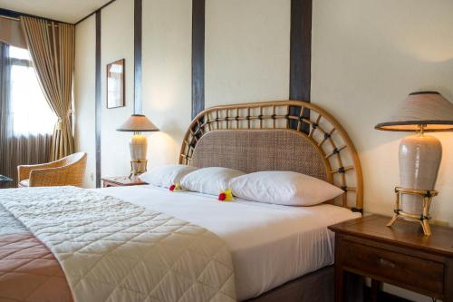 um quarto com uma cama grande com lençóis brancos e almofadas em Toraja Heritage Hotel em Rantepao