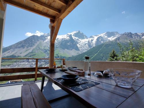 un tavolo su un balcone con vista sulle montagne di Chalet La Gave/La Meije a La Grave