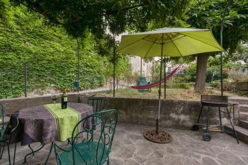 um pátio com uma mesa e um guarda-chuva verde em Gîte vigneron em Félines-Minervois