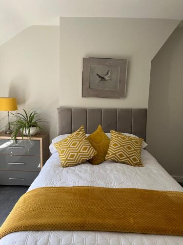 a bedroom with a bed with yellow and white pillows at Newton Road Home A small cosy comfortable 2 bedroom terrace house in Great Meols