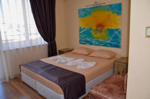 a bedroom with a bed with a painting on the wall at Edelvais Guest House in Primorsko