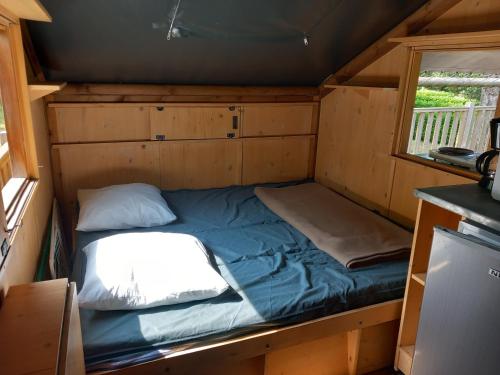 - un petit lit dans une petite maison avec fenêtre dans l'établissement Les Auzerals camping du lac, à Rabastens