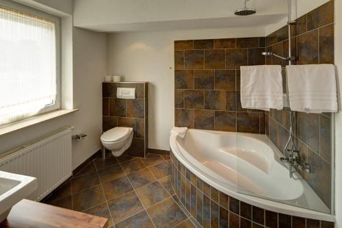 ein Bad mit einer Badewanne und einem WC in der Unterkunft Gästehaus Leimer Bräu in Lenzing