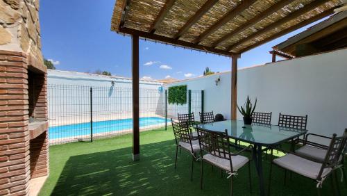 un patio con mesa, sillas y piscina en La Dama del Quijote, en El Toboso