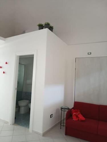 a red couch in a white room with a toilet at Neruda Chic House Sant'Angelo in Sant'Angelo D'Ischia