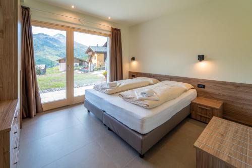 ein Schlafzimmer mit einem Bett und einem großen Fenster in der Unterkunft Arion Apartments - Trepalle in Livigno