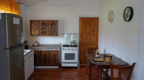 a kitchen with a stove and a table with chairs at Cabañas Isla de Pascua in Hanga Roa