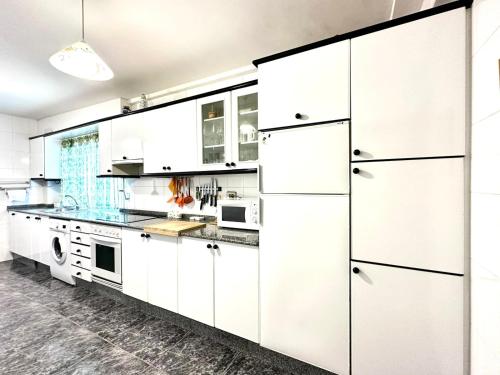 a white kitchen with white cabinets and appliances at Razal in Miño