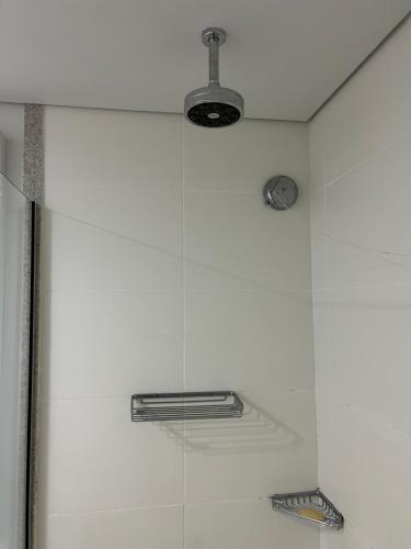 eine Dusche mit zwei Lichtern an einer weißen Wand in der Unterkunft Itaipava Granja Brasil Studio in Itaipava