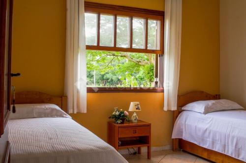 1 dormitorio con 2 camas y ventana en Casa em condomínio com piscina e acesso a represa, en Itaí