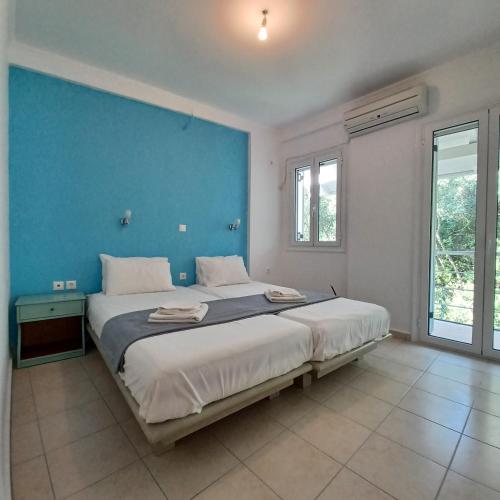 a bedroom with a large bed with a blue wall at NIKOS APARTMENTS and PENTHOUSE in Vasiliki