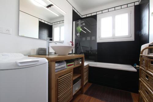 ein Badezimmer mit schwarzen Wänden, einem Waschbecken und einer Badewanne in der Unterkunft La barthe in Biarritz