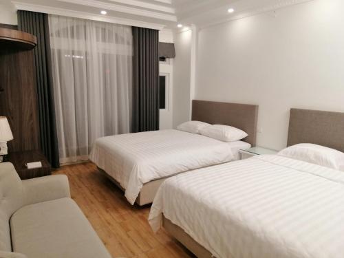 ein Hotelzimmer mit 2 Betten und einem Sofa in der Unterkunft Căn hộ Sao Mai - Nội Bài Hà Nội in Hanoi