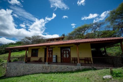 a small yellow house with a red roof at Vilcabamba casa / granja Vilcabamba house / farm in Loja