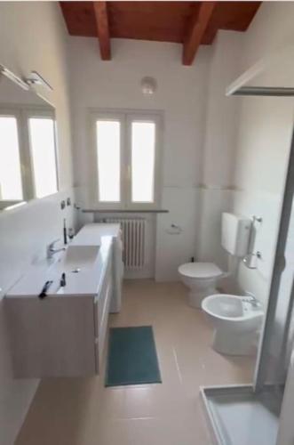 a white bathroom with two sinks and a toilet at Appartamento moderno con 2 camere grandi e lavanderia in Brescello