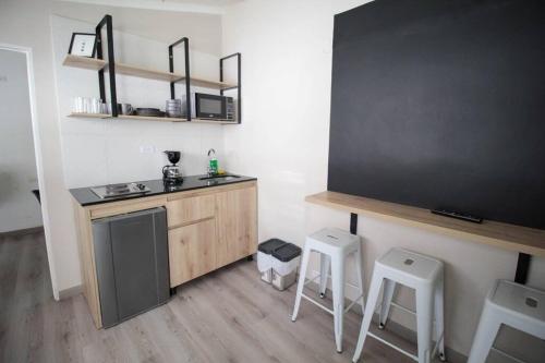 une cuisine avec un évier et un comptoir avec deux tabourets dans l'établissement Hospedaje privado cerca a Provenza en el Poblado - M301 By Roots Rentals, à Medellín