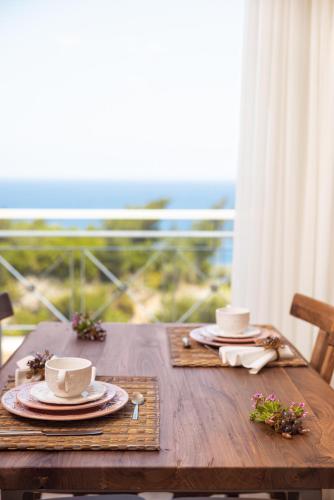 a wooden table with two cups and plates on it at PENNY LUXURY APARTMENTS in Kokkari