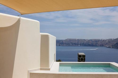 a pool on the side of a house with a view of the water at Apanemo Hotel & Suites in Akrotiri