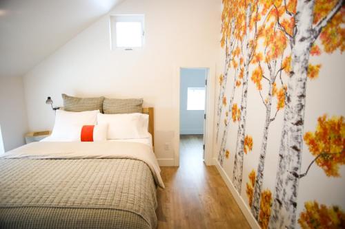 a bedroom with a bed with a tree mural on the wall at Life Elevated Loft: Bright, Prime Location + SAUNA in Salt Lake City