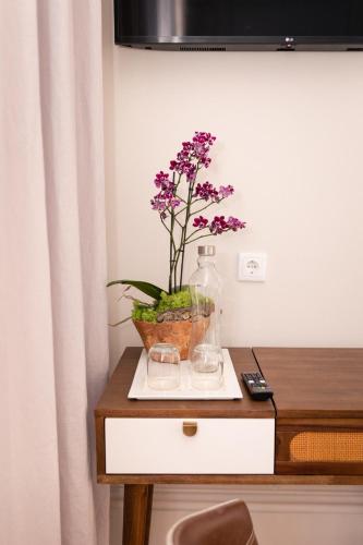 a table with a vase with purple flowers in it at Quinta dos Tojais Hotel Rural in Celorico de Basto