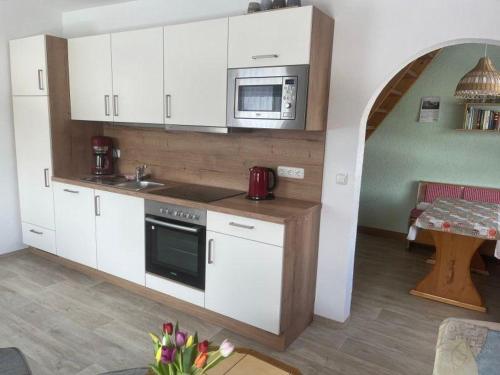 a kitchen with white cabinets and a microwave at Ferienhaus-der-Familie-Demmler in Crottendorf