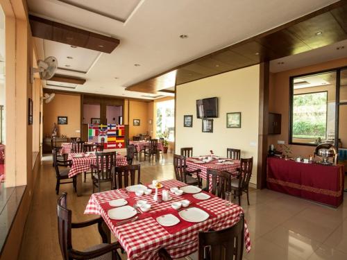 a restaurant with tables and chairs with red and white table cloth at Flag House Resort in Jūnga