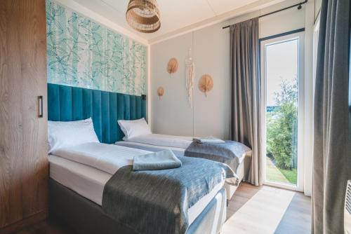 2 camas en una habitación con ventana en RResort - nowe KLIMATYZOWANE domki z PODGRZEWANYM Basenem, Sauna, WiFi, parking w cenie! en Rewal
