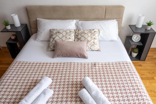 uma cama com lençóis brancos e almofadas em Skopje Station Apartment em Skopje