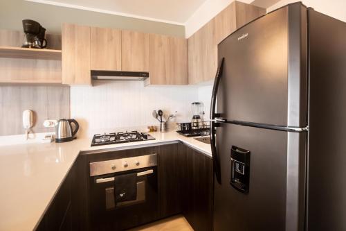 a stainless steel refrigerator in a kitchen with wooden cabinets at El Sol by Wynwood House in Lima