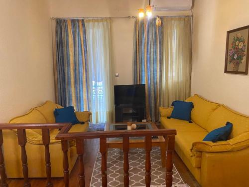 a living room with two yellow couches and a tv at Angolo del Centro in Ágios Rókkos