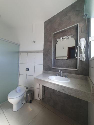 a bathroom with a toilet and a sink and a mirror at Presidente Hotel in Poços de Caldas