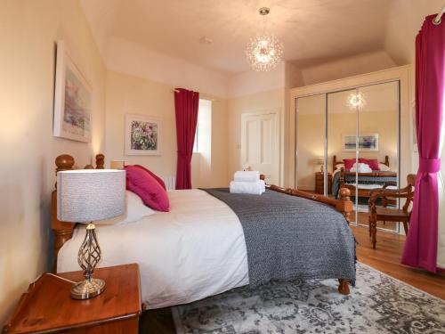 a bedroom with a large bed with red curtains at Holly Leaf Cottage - Drum Castle Estate in Banchory