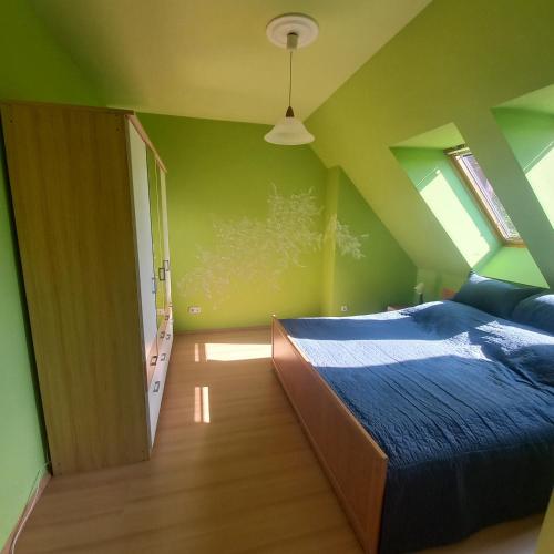 a bedroom with a bed and a green wall at GingerBED Apartman in Kaposvár