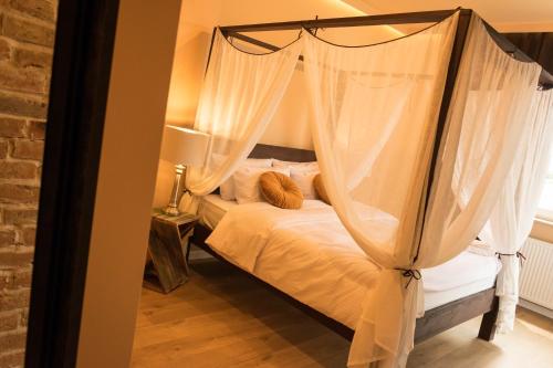 sypialnia z łóżkiem z baldachimem i białymi zasłonami w obiekcie Uniejów Apartments w Uniejowie