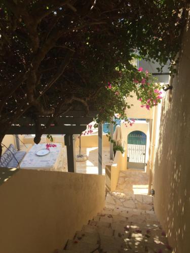 an alley with a table and a tree with pink flowers at The Cove Assos in Asos