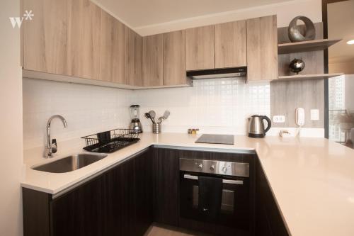 a kitchen with wooden cabinets and a sink at El Sol by Wynwood House in Lima