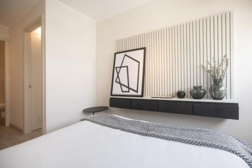 a bedroom with a white bed and a shelf with vases at El Sol by Wynwood House in Lima