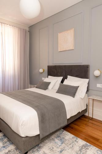 a bedroom with a large bed with white sheets at Quinta dos Tojais Hotel Rural in Celorico de Basto