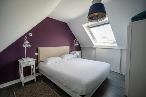 1 dormitorio con cama blanca y pared morada en Le Dixmude, appartement proche plage de Morgat en Crozon