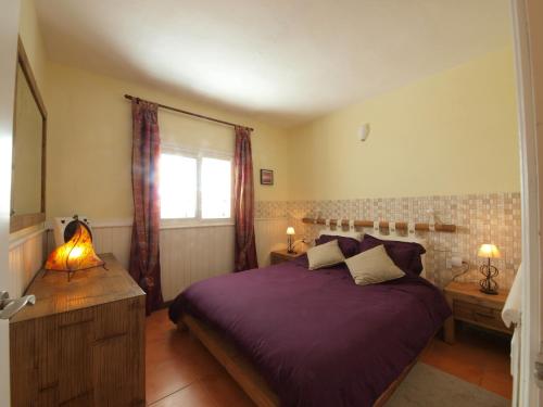 a bedroom with a purple bed and a window at sunrise directly at the sea in La Mareta