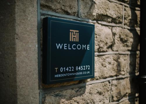 una señal en el costado de una pared de ladrillo en Hebden Townhouse en Hebden Bridge