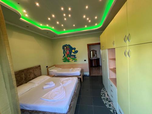 - 2 lits dans une chambre avec des lumières vertes au plafond dans l'établissement Green Garden Villa, à Durrës