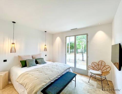 une chambre blanche avec un grand lit et une chaise dans l'établissement Villa standing Uzès,piscine,clim, à Uzès