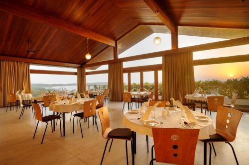 a dining room with tables and chairs and windows at Varanda Do Mar in Panaji