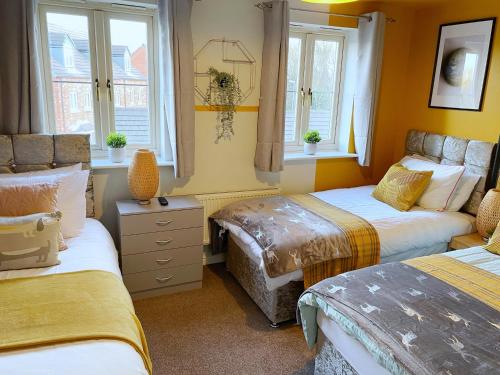 a bedroom with two beds and two windows at Mayflower House Barnsley-Wombwell-3 Bedrooms-2 Showers-Longer Stay- Free Parking in Barnsley