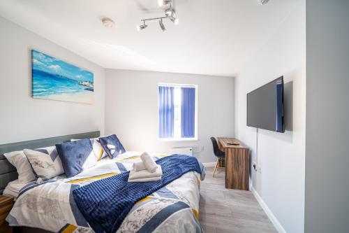 a bedroom with a bed and a flat screen tv at BV Studios with Ensuite Showers & Share Kitchens Prime Location near Hospital, Town Center Apt 4 in Saint Helens