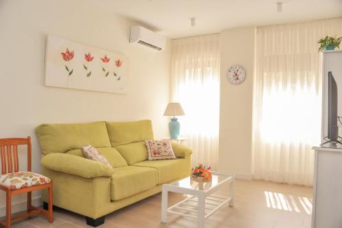 a living room with a yellow couch and a table at Ramón y Cajal by TheGoodTourist in Seville