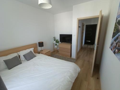a bedroom with a white bed and a television at Apartament Stogi in Gdańsk
