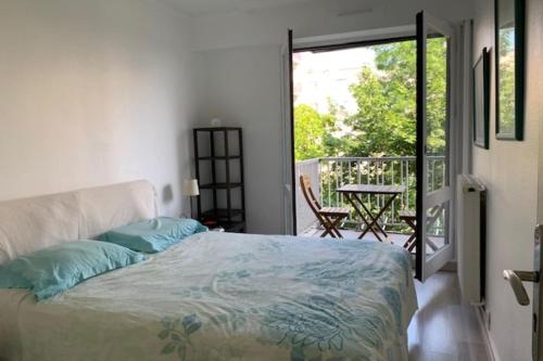 a bedroom with a bed and a balcony with a table at Spacious cocoon near the Place de la Nation in Paris