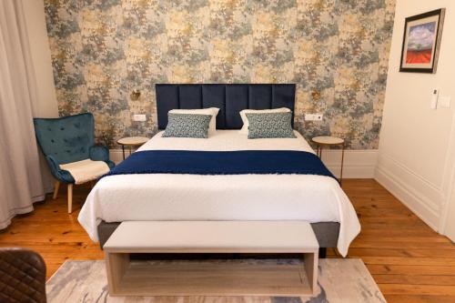 a bedroom with a large bed and two chairs at Quinta dos Tojais Hotel Rural in Celorico de Basto